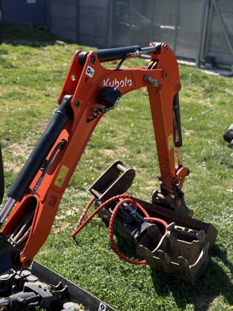 Detail hydraulického ramene mini bagru Kubota K008-3 s lžící pro přesné výkopové práce.